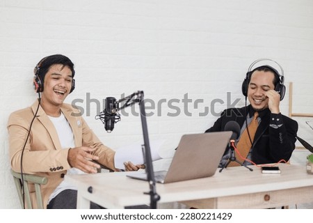 Radio host and businessman having fun and laughing during interview at podcast room. 