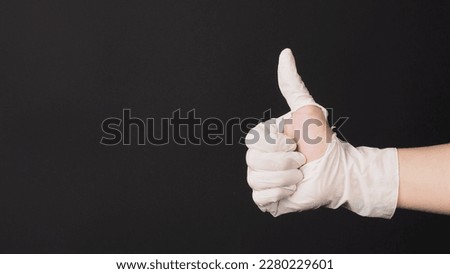 Like hand sign and wear torn glove on black background.