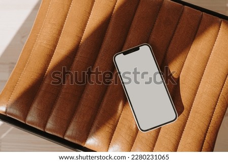 Flatlay mobile phone on orange leather bench with sunlight shadows. Aesthetic elegant blog, online shopping, online store, social media branding template with blank copy space