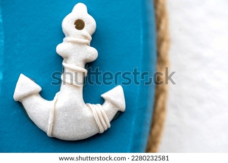 Ship anchor in white on blue background.