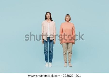 Full body smiling happy fun cheerful cool confident elder parent mom with young adult daughter two women together wear casual clothes look camera isolated on plain blue background. Family day concept Royalty-Free Stock Photo #2280234201