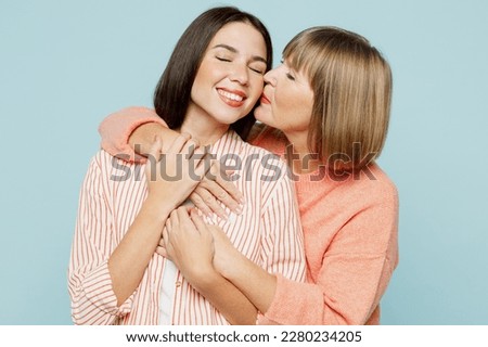 Positive lovely fun elder parent mom with young adult daughter two women together wearing casual clothes hugging cuddle kiss isolated on plain blue cyan background. Family day tender moments concept Royalty-Free Stock Photo #2280234205