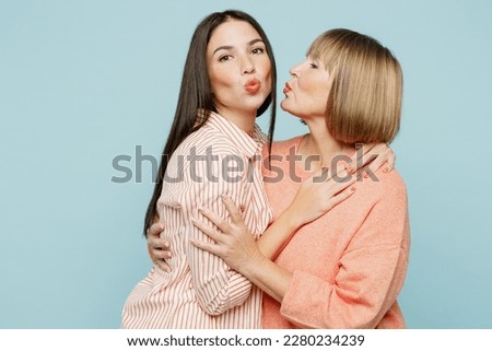 Side view adorable lovely satisfied elder parent mom with young adult daughter two women together wearing casual clothes hug cuddle goign to kiss isolated on plain blue background. Family day concept