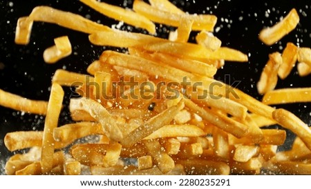 French fries - fried potatoes flying. Fly fastfood isolated on black background. Royalty-Free Stock Photo #2280235291
