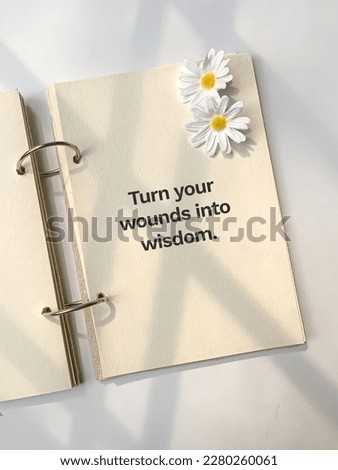 Inspirational life quote on a white page of a book with white flowers