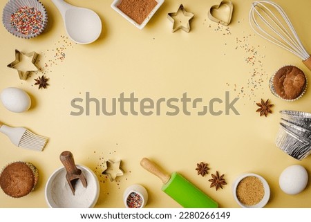 Baking or cooking colorful background. Ingredients, kitchen items for baking. Kitchen utensils, flour, eggs, sugar and muffins. Text space, top view.