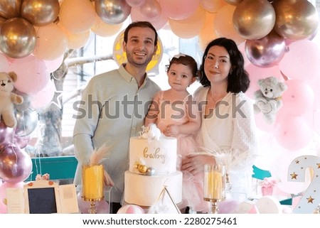 Mother, father and daughters posing in front of 2nd birthday party decor. Lifestyle family portrait. Royalty-Free Stock Photo #2280275461