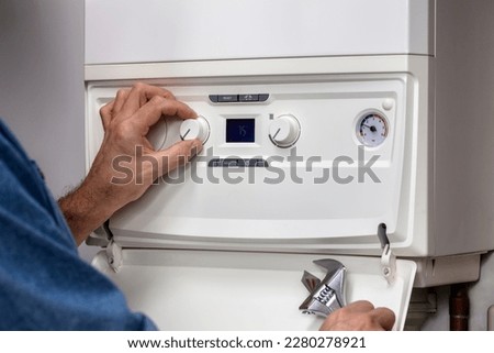 Plumber technician servicing or repairing home central heating system boiler Royalty-Free Stock Photo #2280278921