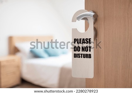 Do not disturb sign on hotel room or apartment door with bedroom and bed in background Royalty-Free Stock Photo #2280278923