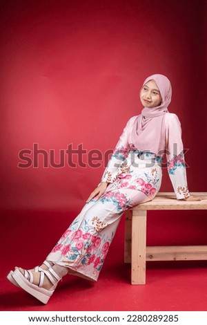 Young smiling confident asian muslim woman in hijab over isolated over background studio. Casual hijab fashion. 
