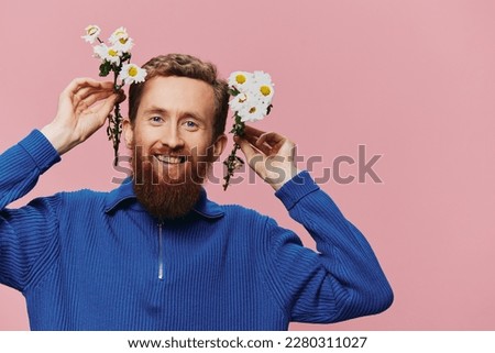 Portrait of a funny man smiling with a bouquet of flowers daisies on pink isolated background, copy place. Holiday concept and congratulations, Valentine's Day, Women's Day.
