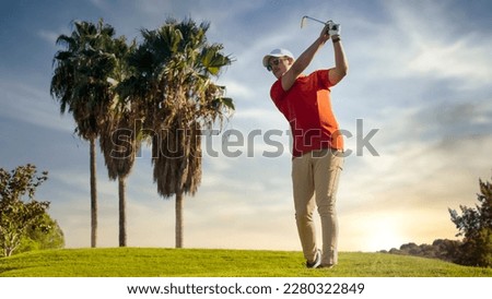 Golf shot man off the tee on a hole on the golf course. golfer heading out shot with long iron at sunset wearing glasses and visor with palm trees in the background. blur background