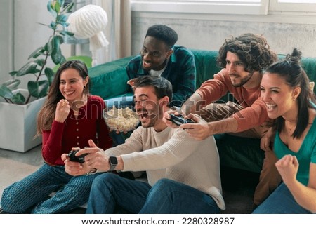 Group of friends play video games together at home, having fun. Royalty-Free Stock Photo #2280328987