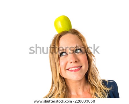 Blonde girl with apple above her head over white background