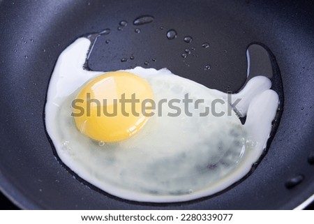 An egg being fried in a nonstick pan Royalty-Free Stock Photo #2280339077