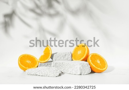 Beauty skin care product presentation podium and display made with porous stones and oranges on white sunny background. Studio photography. Royalty-Free Stock Photo #2280342725
