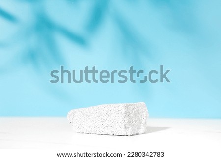 Neutral white blue product presentation podium and display made with porous stone. Studio photography.
