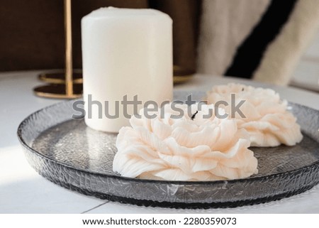 Decorative candle in the form of a flower on a glass stand. A candle in the form of a rose or a peony on a table. Details of decorative interior design elements. Royalty-Free Stock Photo #2280359073