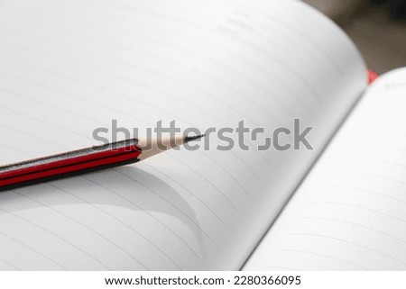 A wooden pencil placed on an opened book. Edited photo.