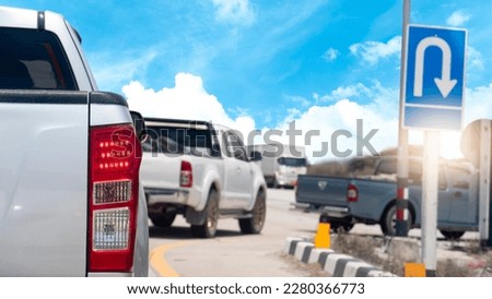 Rear side of pickup car stop and brake on the road. Wait for another car to make a U-turn. Blurred image of two cars parked in reverse in front. With blur sign baord of U-Turn.