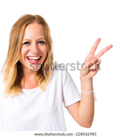 Cute woman doing victory gesture over white background