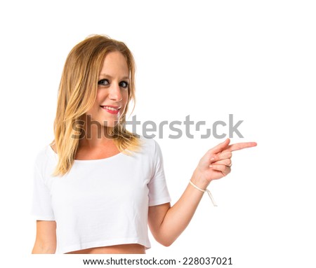 Blonde woman pointing to the lateral over white background