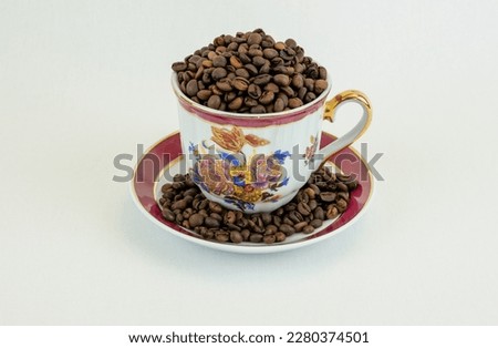 Coffee cup and saucer with coffee beans on white background