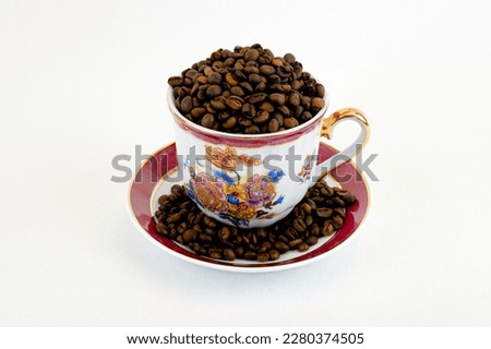 Coffee cup and saucer with coffee beans on white background