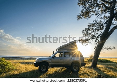A 4x4 camper with rooftop tent is staying on the beach at sunset Royalty-Free Stock Photo #2280375091