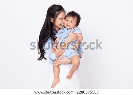 Asian mom hold baby smile and kissing on baby cheek happiness moment together isolated on white background. Healthy Mother and baby boy smile and laughing spending time together positive and cheerful.
