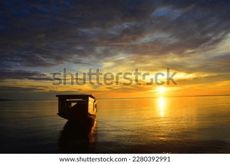 Photo of a wooden ship with a sunset and calm sea in the background