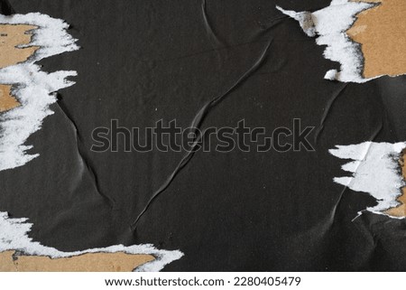 Ripped black paper on cardboard background