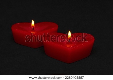 two red candles in the form of hearts on a black background (valentine's day)