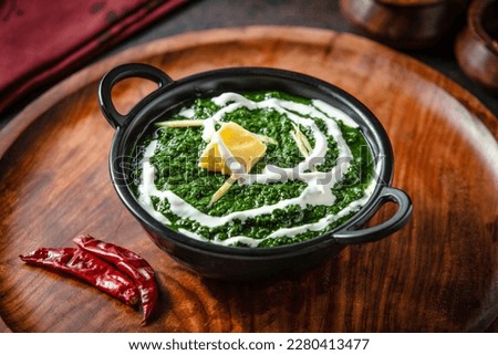 Palak Paneer is a popular North Indian dish that consists of soft chunks of paneer cheese simmered in a smooth and creamy spinach gravy. Royalty-Free Stock Photo #2280413477