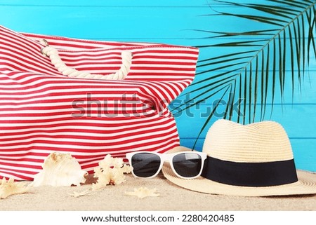 Summer hat, bag, with sunglasses, seashells and palm leaf on blue background