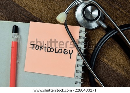 Concept of Toxicology write on sticky notes with stethoscope isolated on Wooden Table.