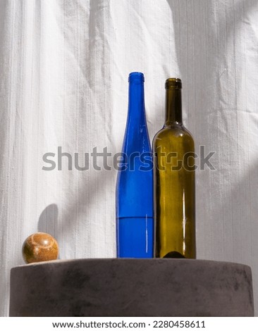 Blue and green transparent wine bottles, marble ball on whetstone