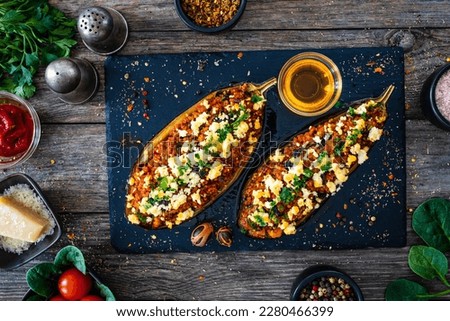 Roasted aubergine stuffed with minced meat and cheese on wooden table Royalty-Free Stock Photo #2280466399