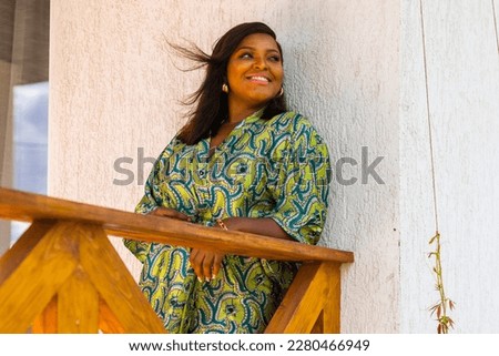 African american woman relaxing and enjoying sun while standing at terrace or balcony at sunlight at summer. Slow living and tranquil moment and mental health. Backyard terrace vacation weekend