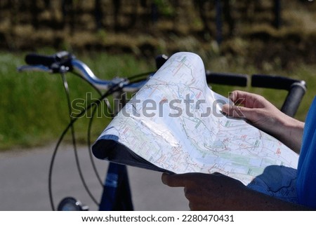 Person looking for orientation on a cycling map, in the background bicycles Royalty-Free Stock Photo #2280470431