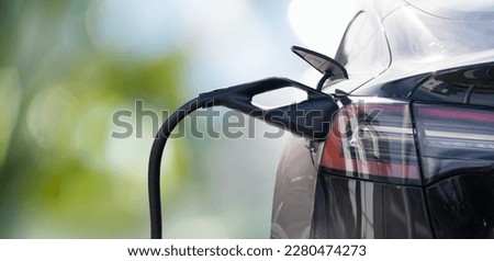 Close up of electric car inlet with a connected charging cable on a green background Royalty-Free Stock Photo #2280474273