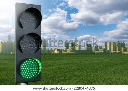 Green traffic light on a background of green city. Symbol of sustainable energy and development