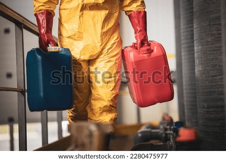 Unrecognizable chemicals worker carrying plastic canisters inside factory.