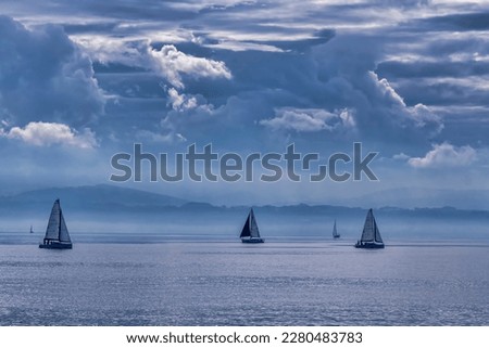 Dramatic sky over Lake Constance. The outlines of mountains, rare silhouettes of sailboats are visible on the horizon.