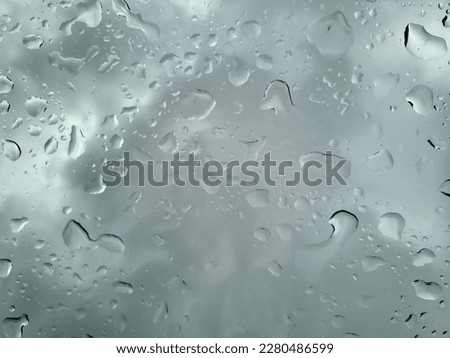 Background of cloudy sky and raindrops on glass