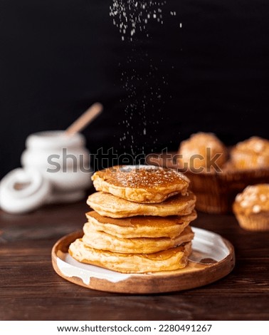 Fried fluffy pancakes with powdered sugar, on a black background, in a cozy grandmother's kitchen, home baking, with honey, oatmeal muffins Royalty-Free Stock Photo #2280491267