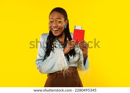 Vacation Travel. Joyful African American Lady Holding Passport And Boarding Pass Posing On Yellow Studio Background, Smiling To Camera. Female Tourist Advertising Cheap Tickets Offer Concept