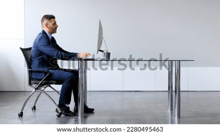 Side view of middle aged male manager working on computer in office, sitting at desk and using pc, looking at screen, panorama with free copy space Royalty-Free Stock Photo #2280495463