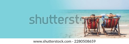 Romantic lovers young couple relaxing sitting together on the tropical beach looking to the sea.Summer weekend vacation,travel with web banner advertising copy space blue background for add text