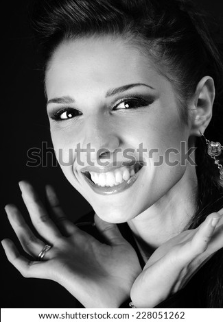close up portrait of of Young teenage beautiful smiling model with her hands framing her face in black and white